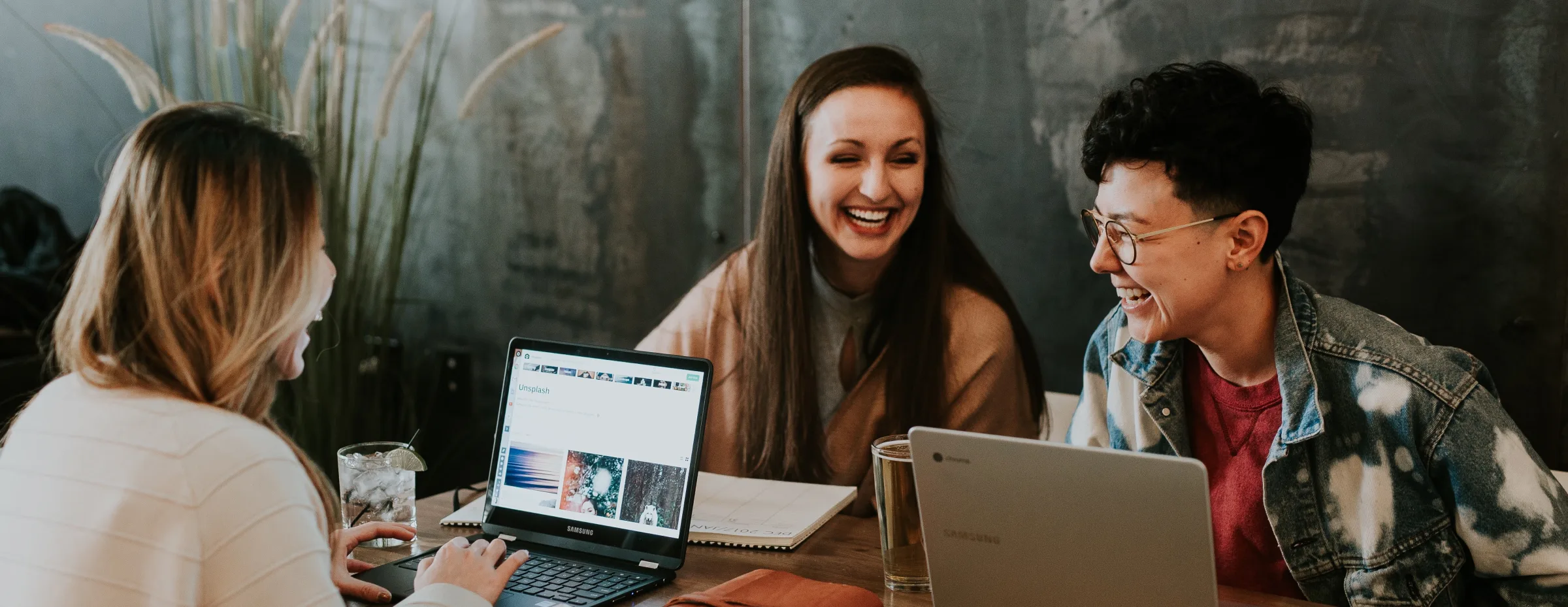 A man and a woman sitting at a table in a working environment and laughing
