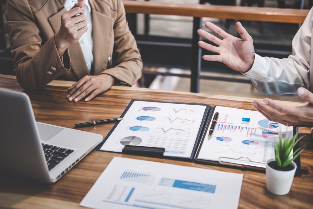 Two colleagues discussing business performance data at a table