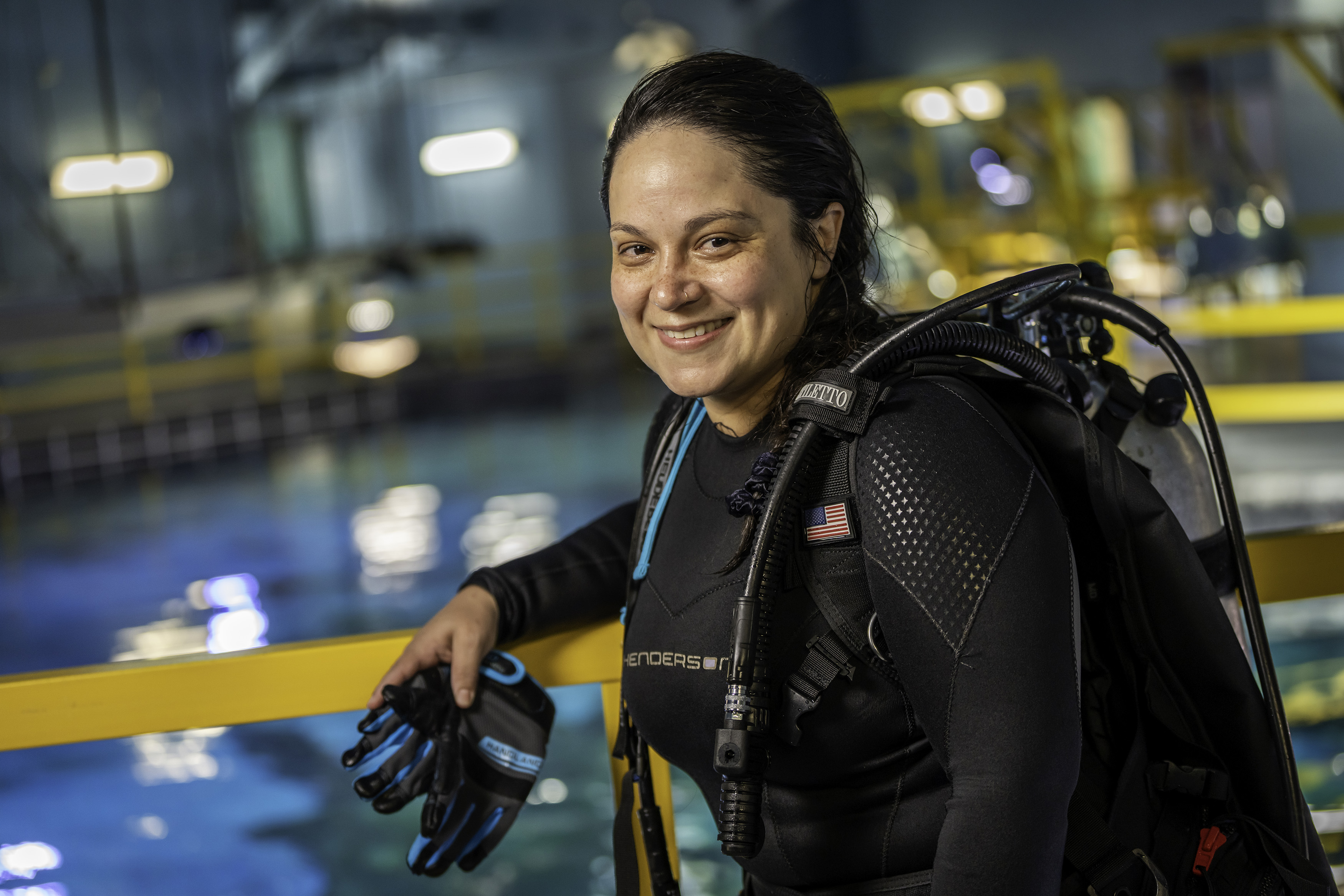 Diver wearing scuba equipment beside an indoor training pool