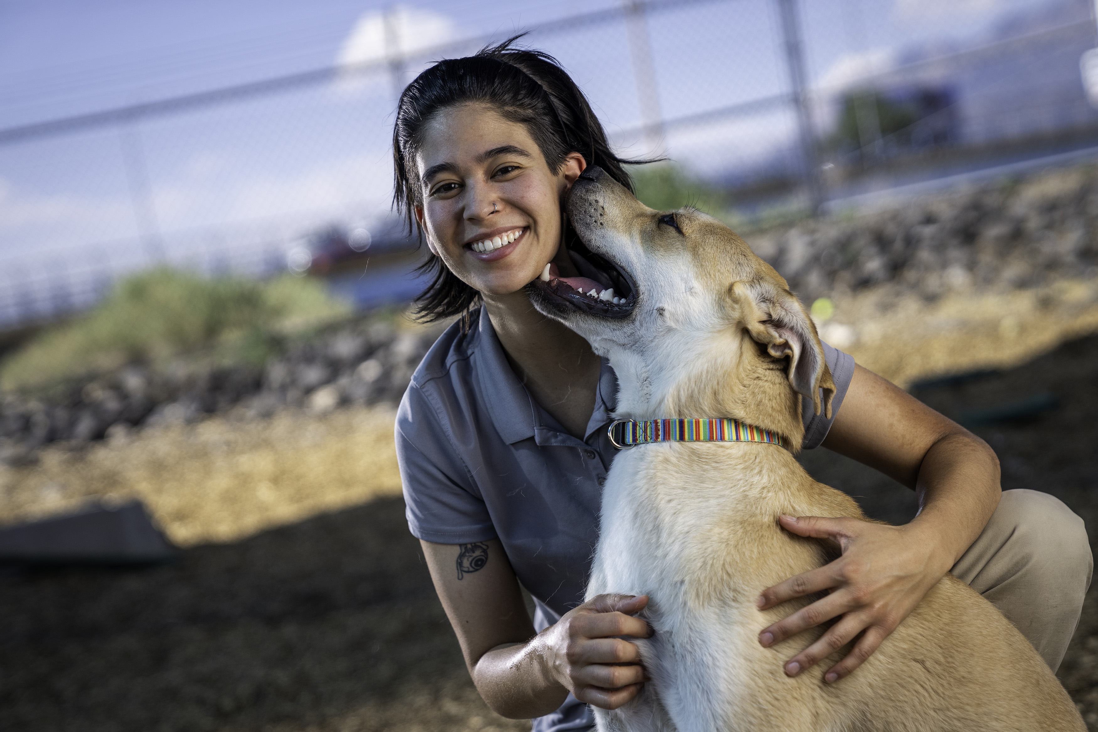 Animal care worker smiling as a dog nuzzles her face