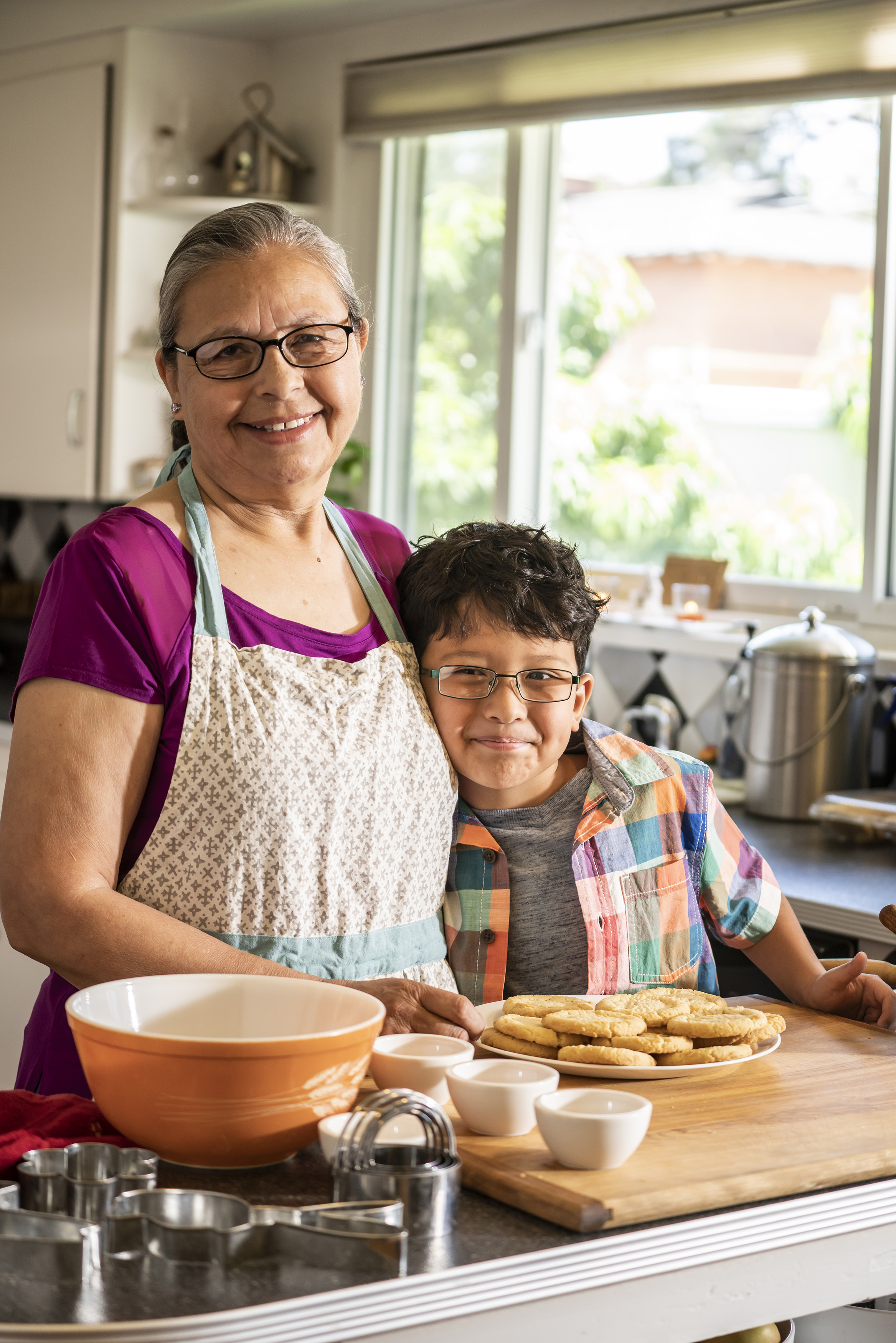 Woman and young boy smiling together while baking in a kitchen