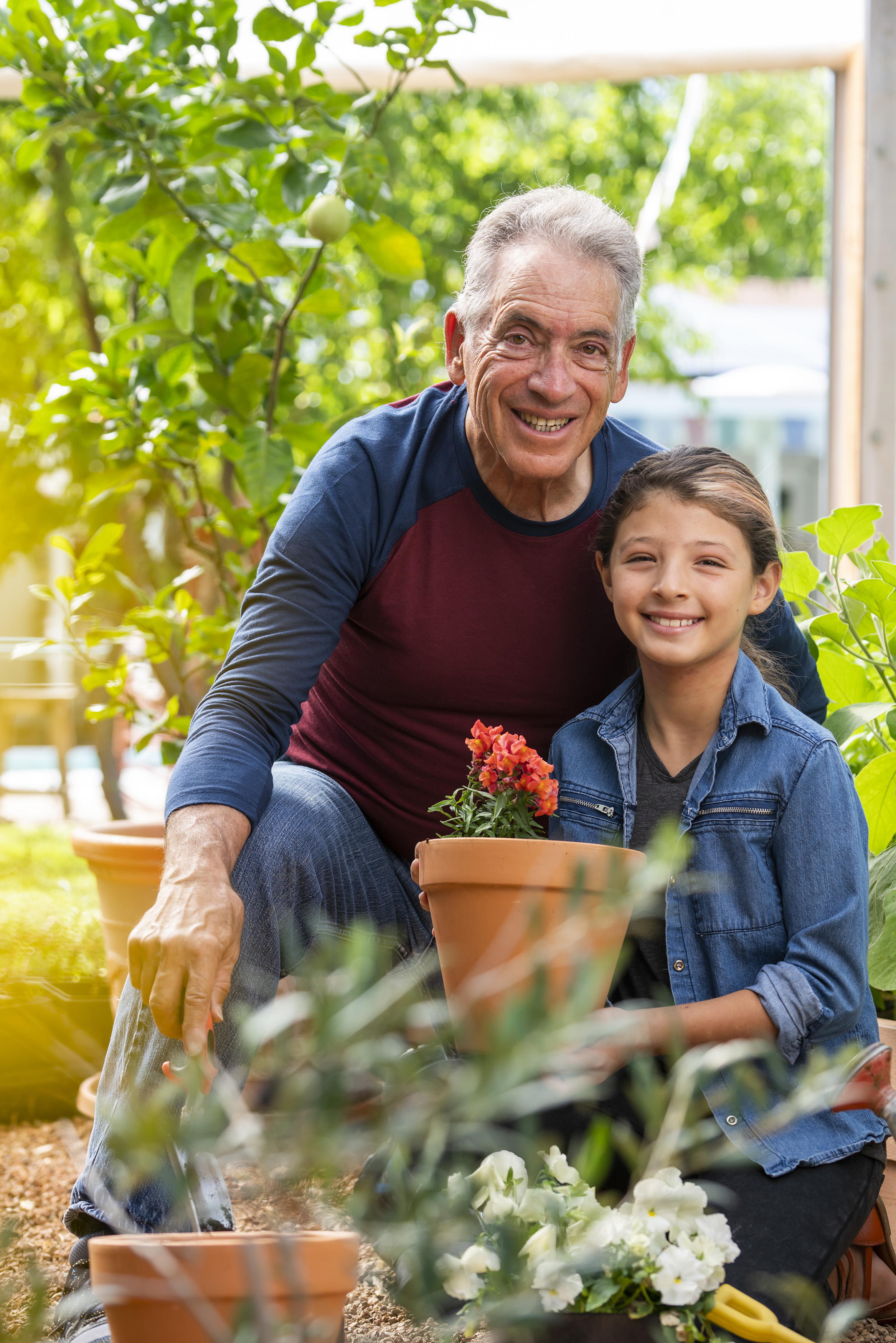 Older man and young girl smiling together while gardening