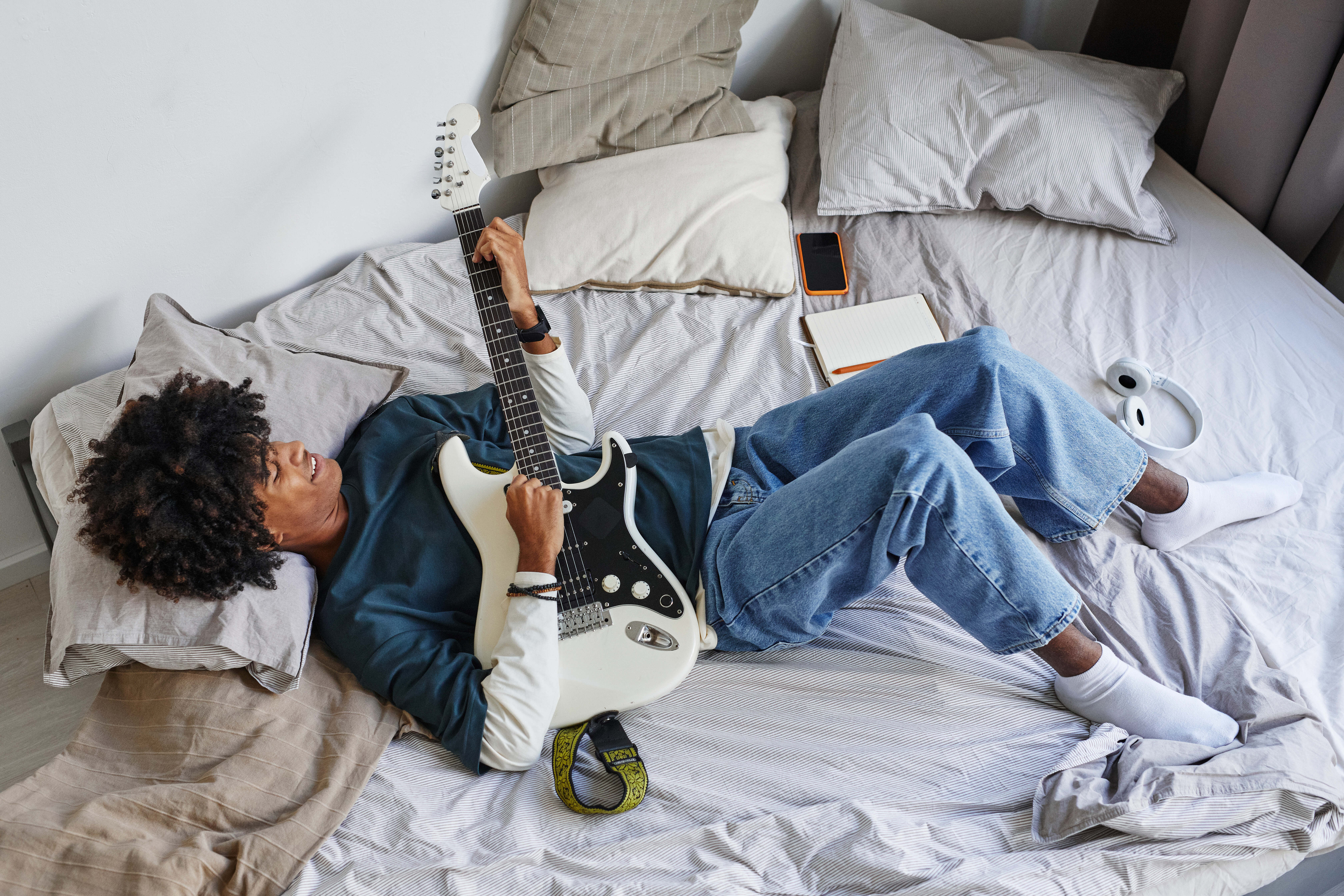 Man on bed with guitar stock image