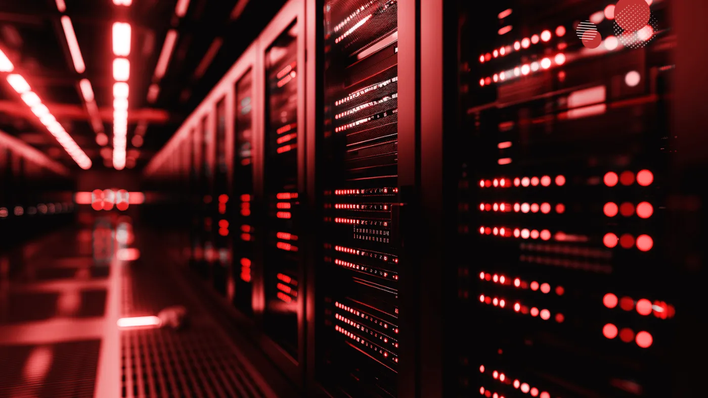 Dois técnicos em TI, vestidos com camisas e bonés vermelhos, trabalham atentamente em frente a racks de servidores em um ambiente de data center. Eles monitoram ativamente os processos no laptop e em uma tela adicional, focados na migração eficiente para servidores cloud, destacando a complexidade e a importância desta operação para a modernização de infraestruturas de TI.