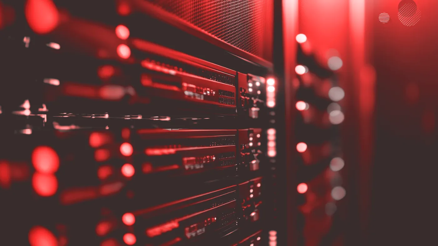 A imagem apresenta uma fileira de servidores iluminados em tom avermelhado, representando o conceito de load balance. Essa técnica distribui a carga de trabalho entre vários servidores, garantindo maior eficiência e estabilidade na infraestrutura de TI, evitando sobrecarga e assegurando a disponibilidade contínua dos recursos.
