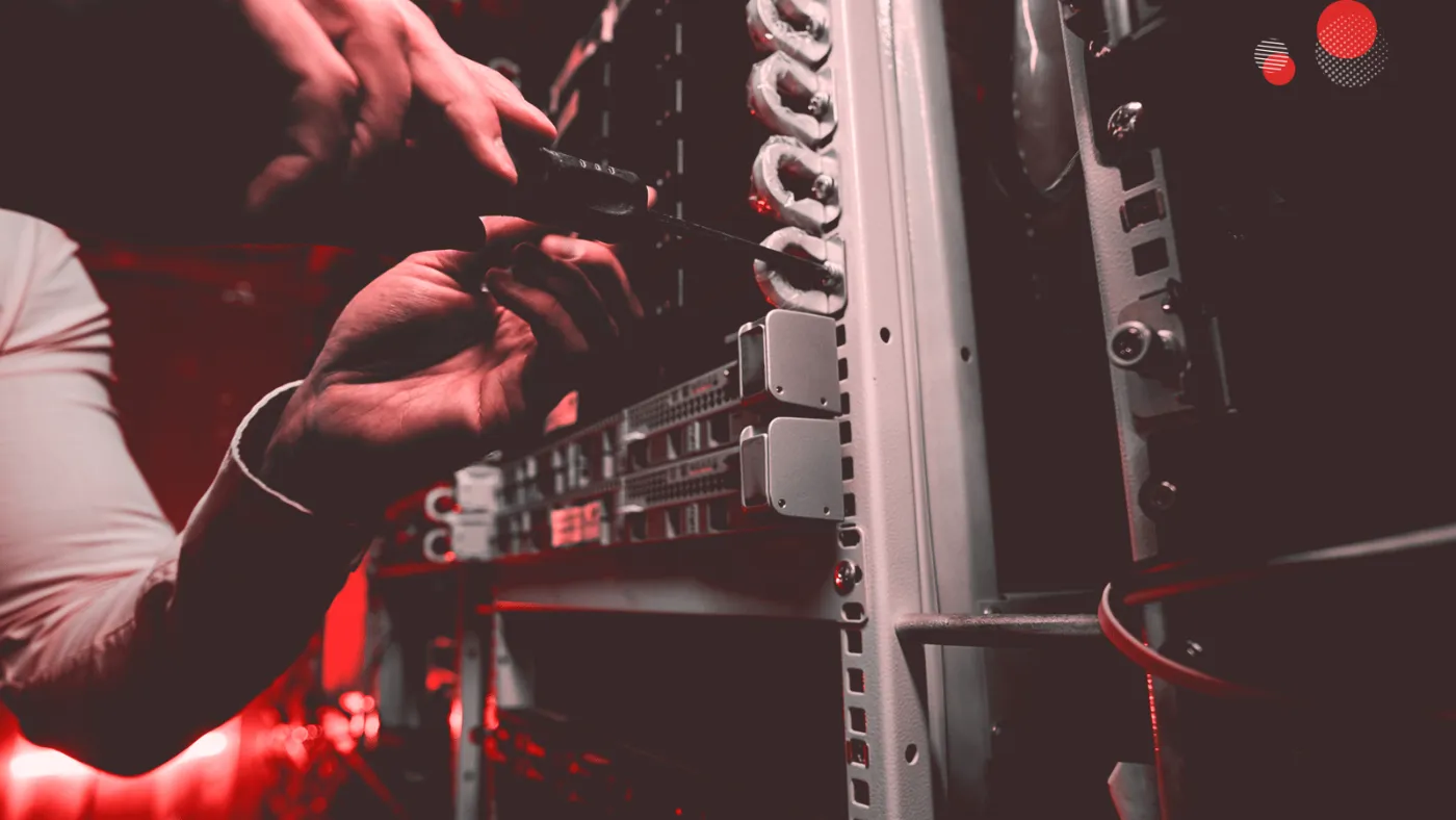 Mão conectando cabos em um servidor físico, representando infraestrutura on premise em ambiente de data center.
