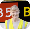 Woman wearing a yellow safety vest smiling against a background with red and black colors.