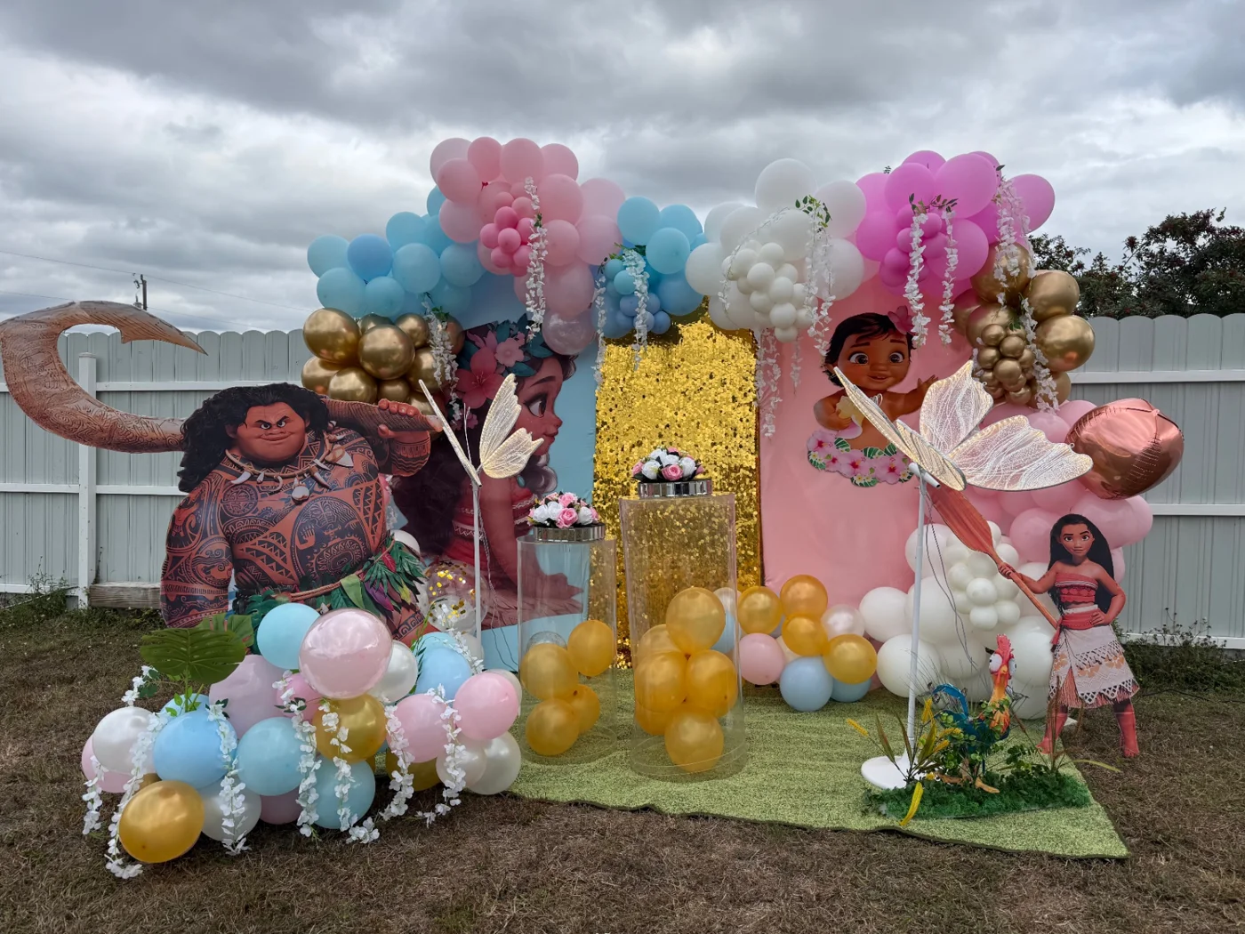 Outdoor character-themed display with pink panels, gold backdrop, pastel balloons, flowers and character cutouts.