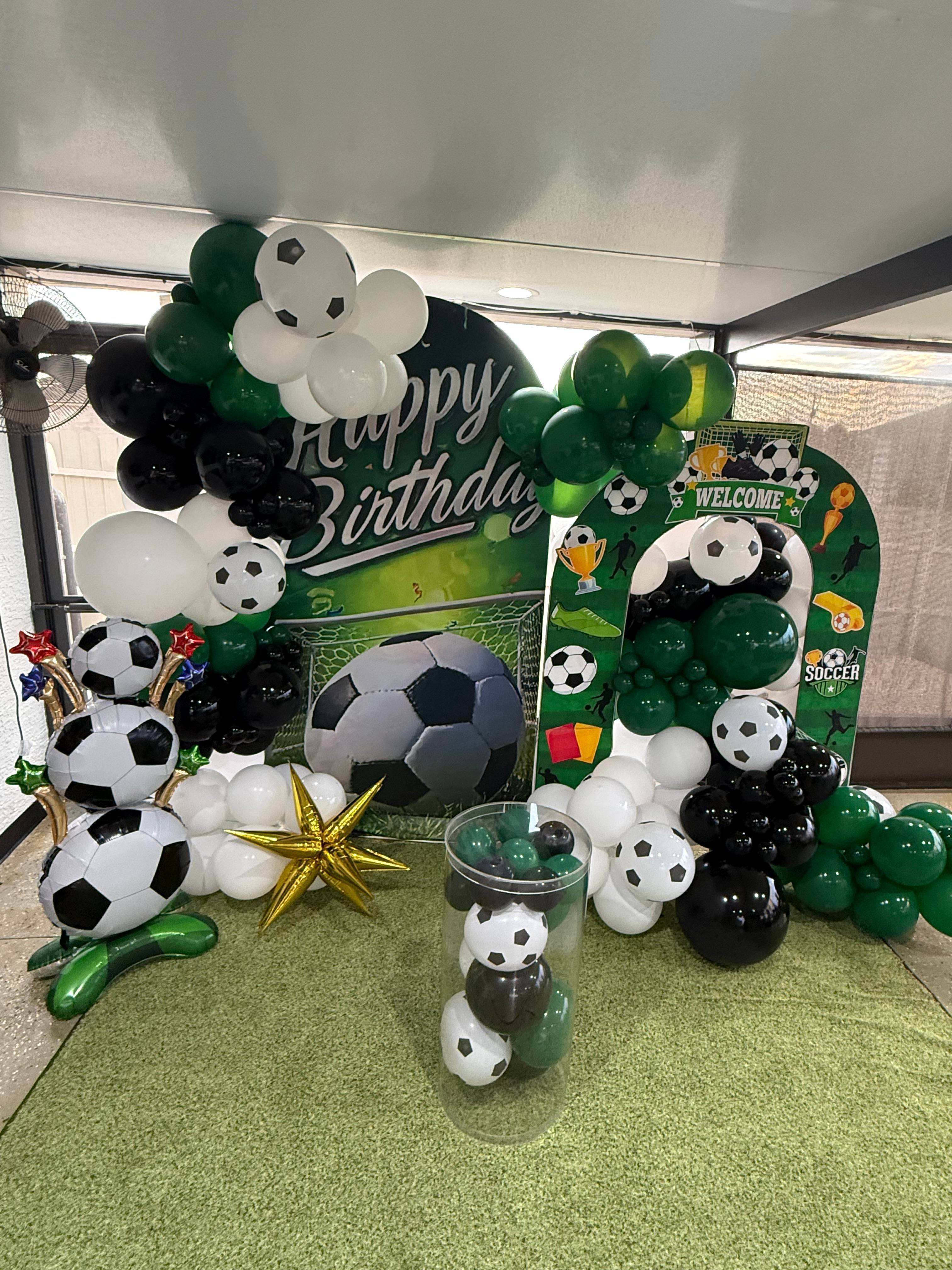 Soccer-themed party display with green, black and white balloons and soccer graphics.