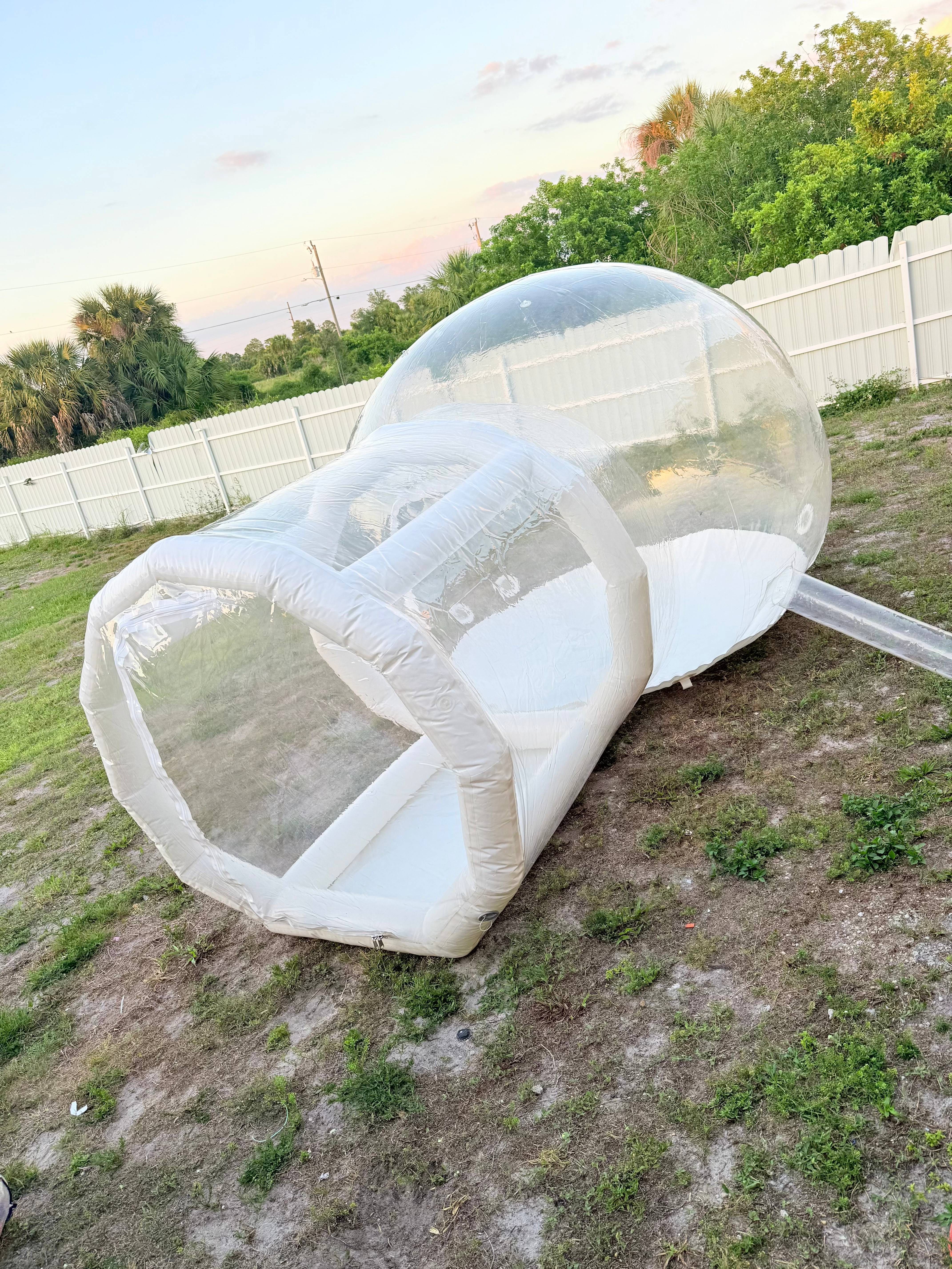 Transparent white-trimmed bubble inflatable set up on grass.