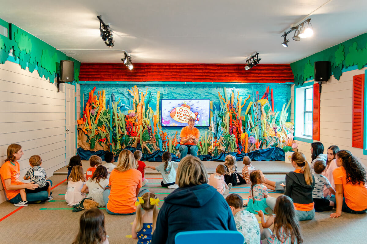 Preschoolers sitting on the floor watching the large group Bible story in Waumba Land