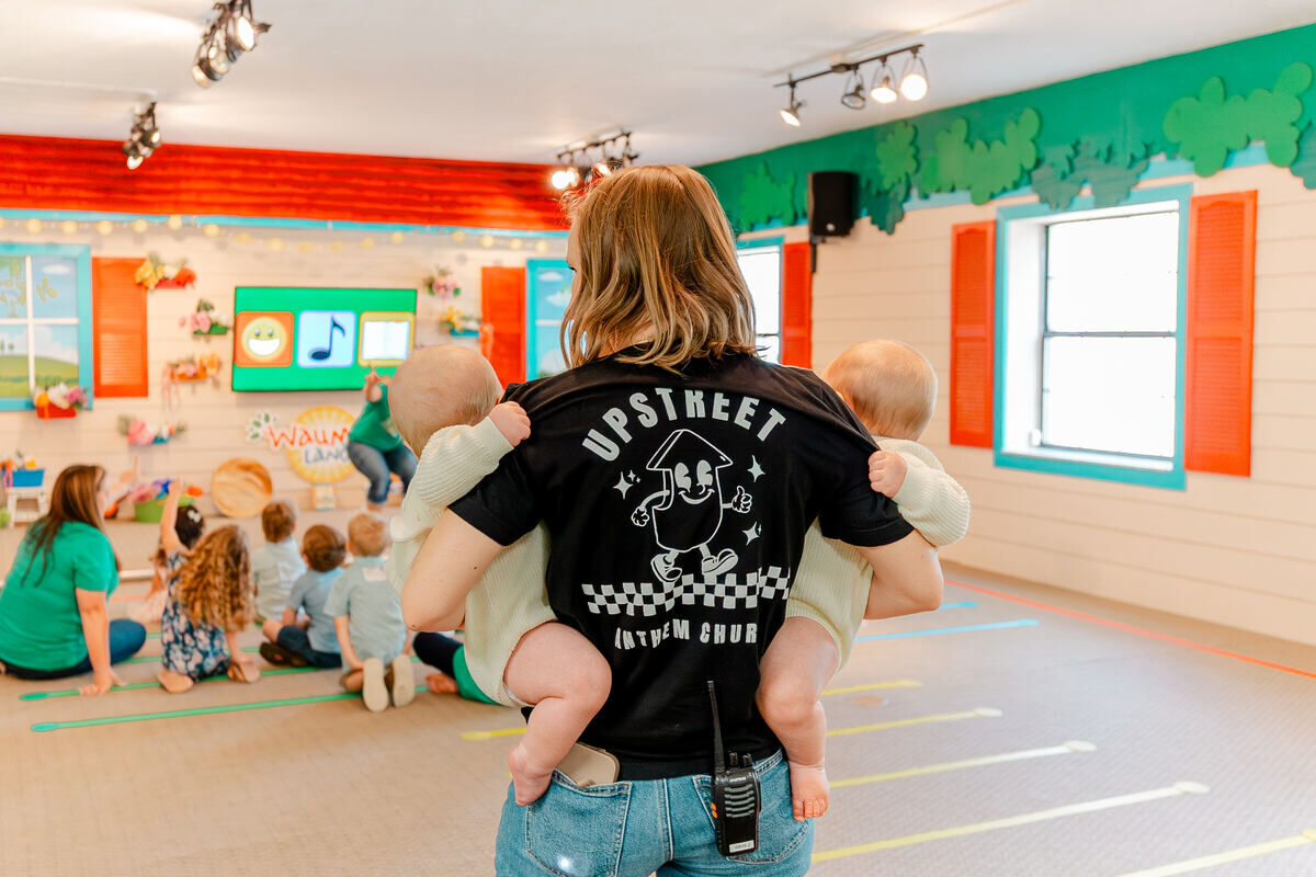 A volunteer carrying a baby through the Waumba Land room while toddlers play
