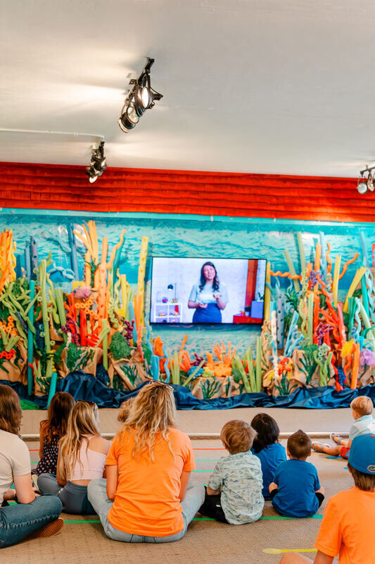 Toddlers sitting on the rug watching the Bible story screen in Waumba Land