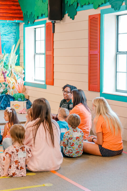 Leaders sitting on the floor with preschoolers during small group in Waumba Land
