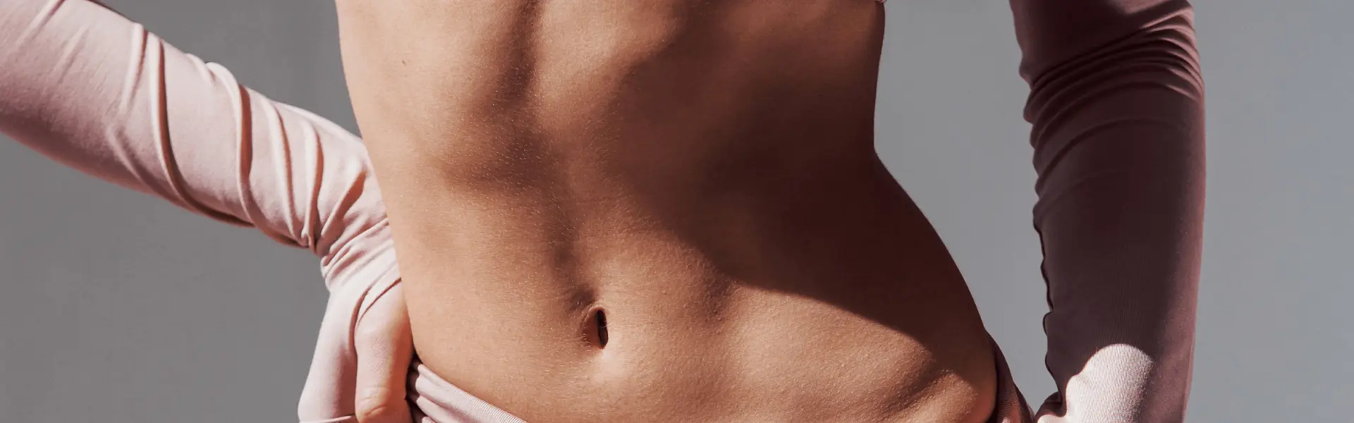 Person with their abdomen exposed and hands resting at their hips