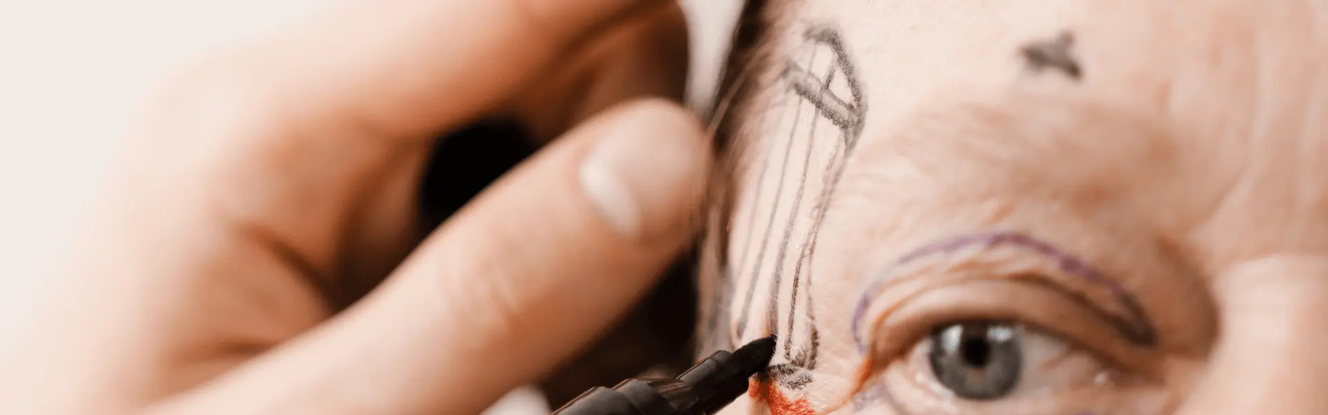 Close-up of an eyebrow with markings and a pencil held beside it.