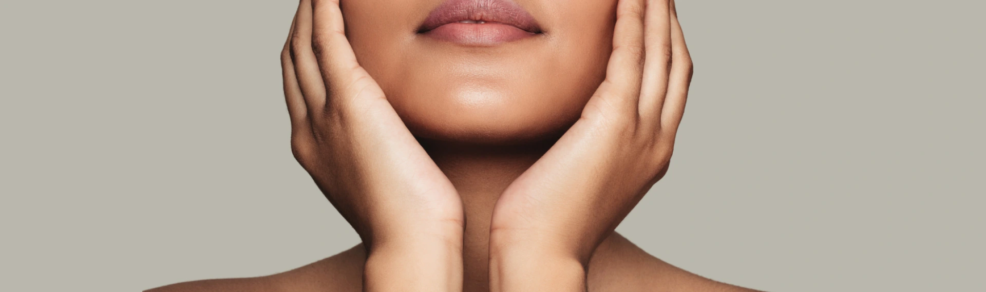 Woman framing her chin and cheeks with both hands.