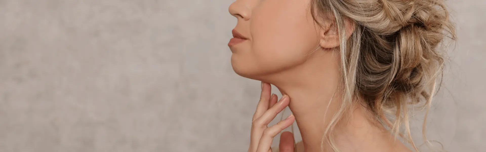 Side profile of a woman with her hand resting on her neck.