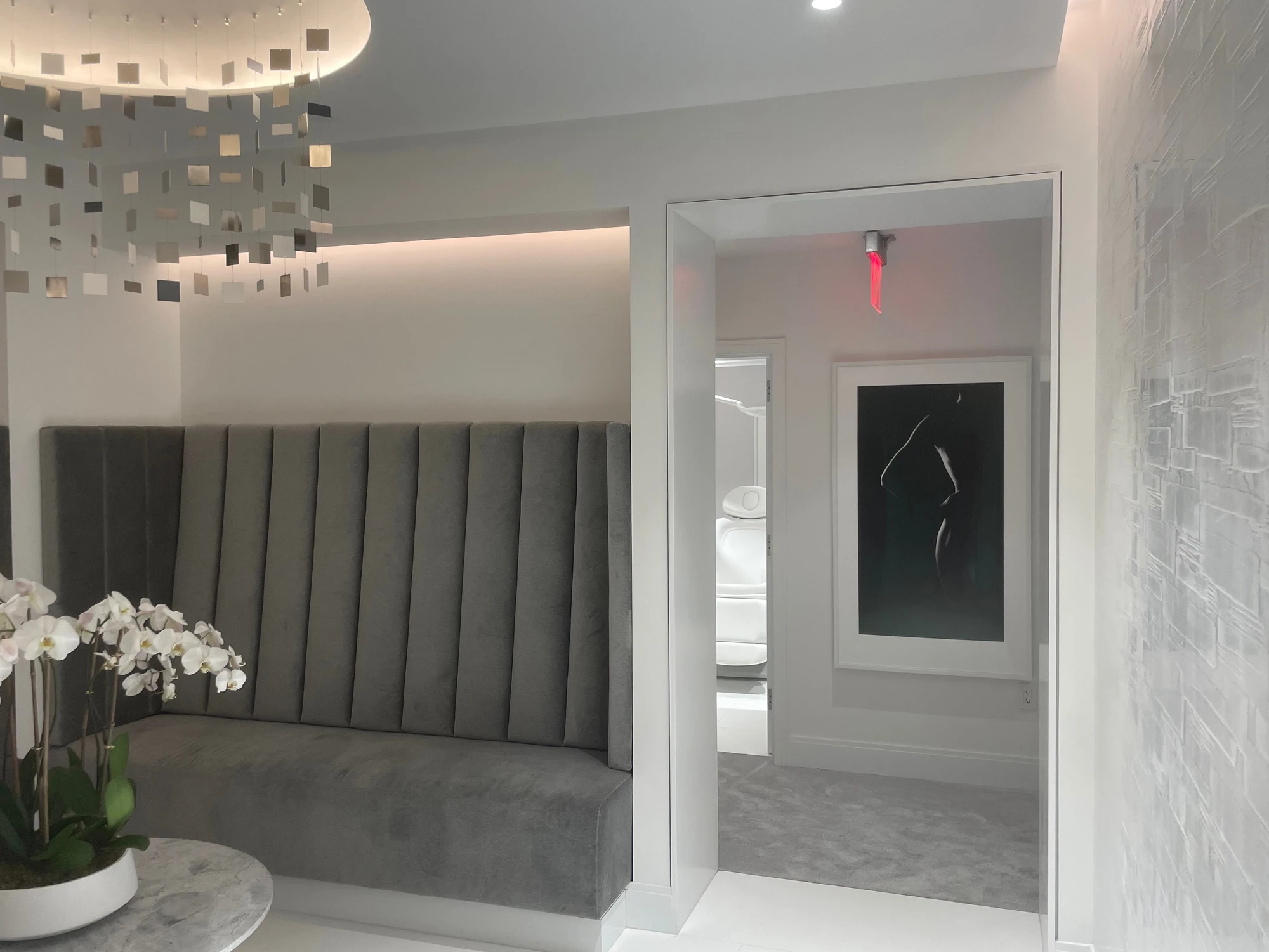 Practice entry with upholstered seating, orchids, and a view into a treatment room.