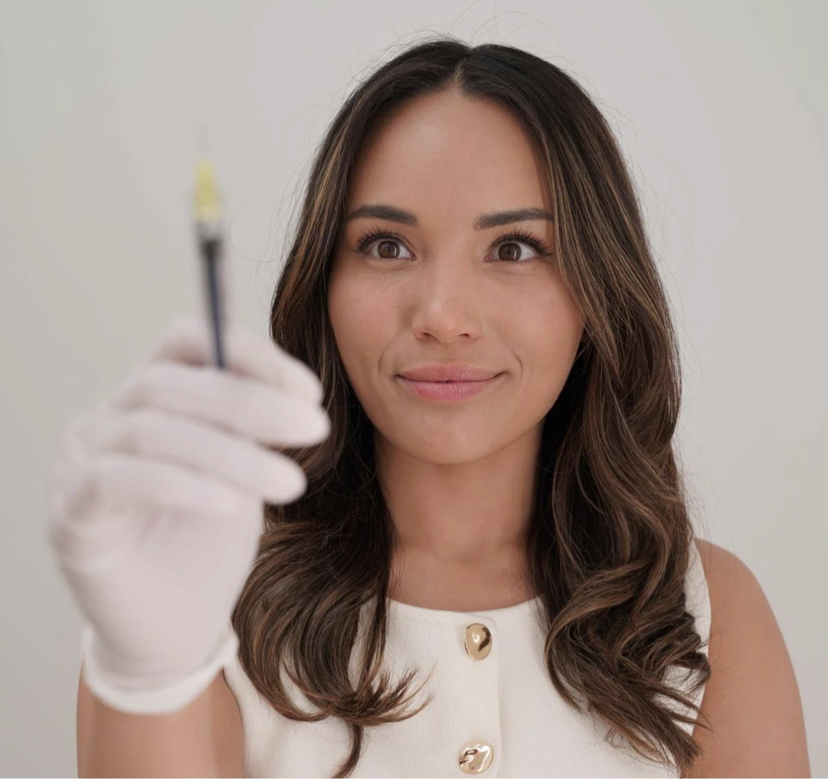 Leah holding a syringe with a gloved hand
