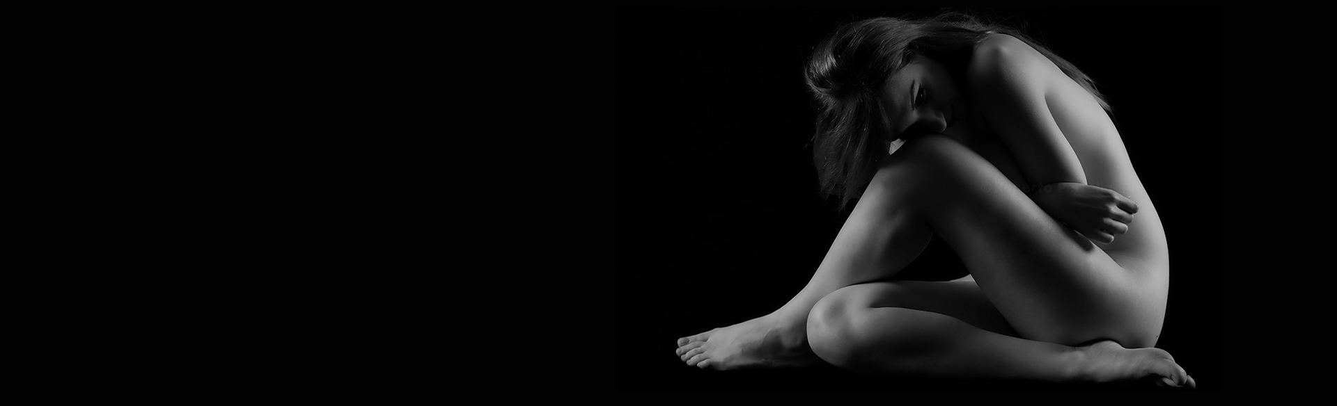 Black-and-white silhouette of a seated woman in a curled pose