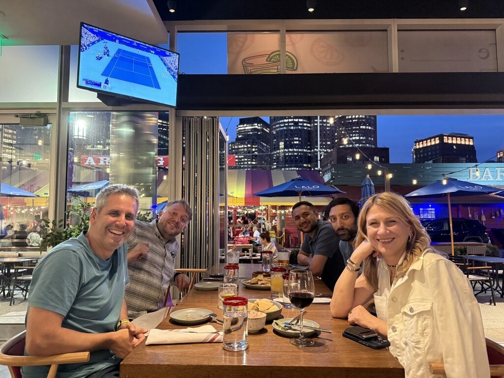 Imply team members at dinner on a patio at dusk