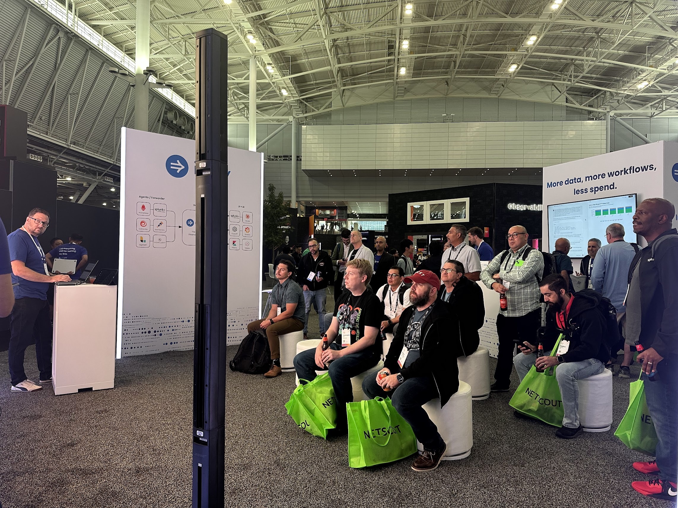 Attendees seated and standing near the Imply booth at Splunk .conf25.