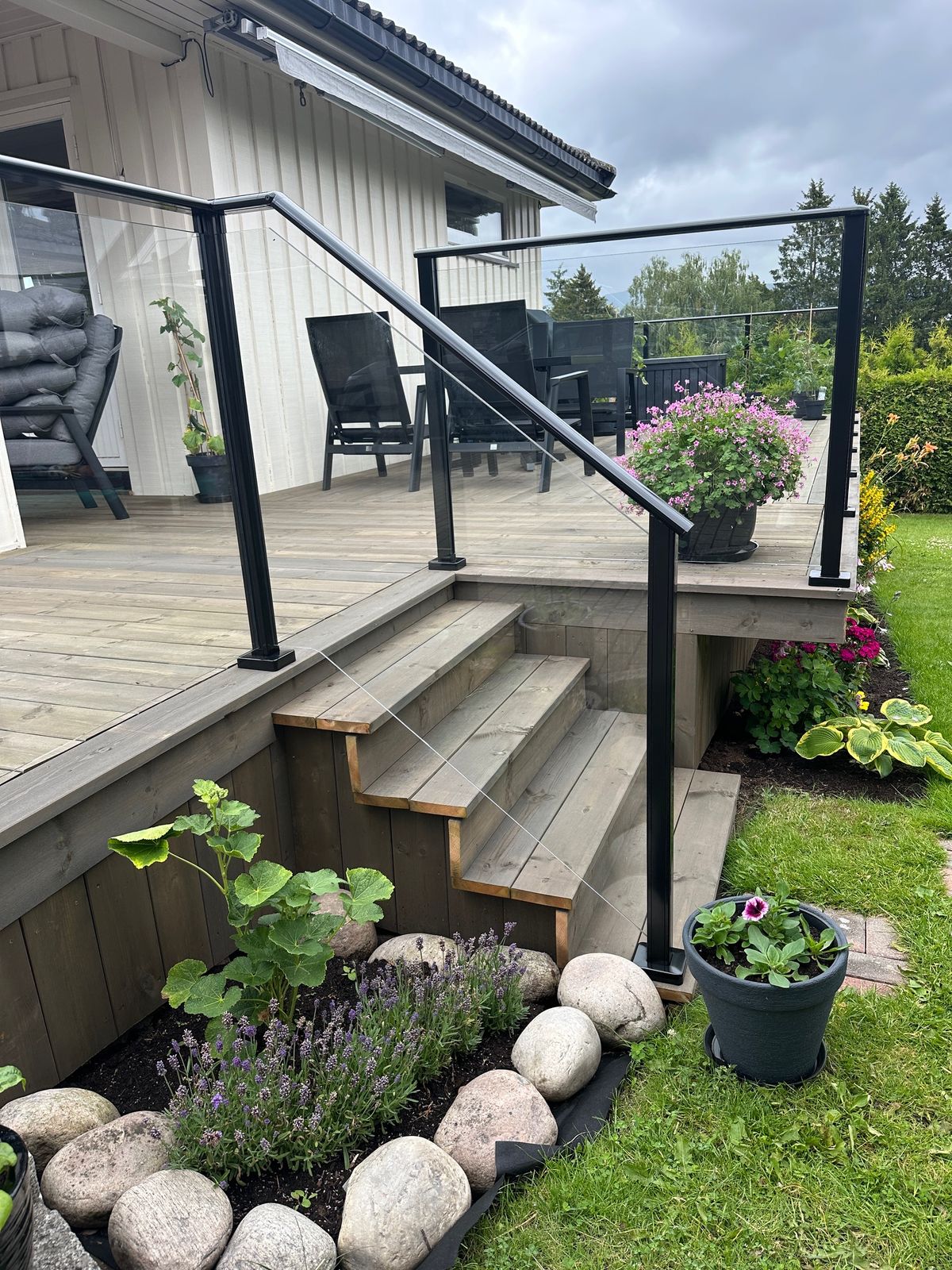 Terrasse med trapp og rekkverk i glass og sort metall