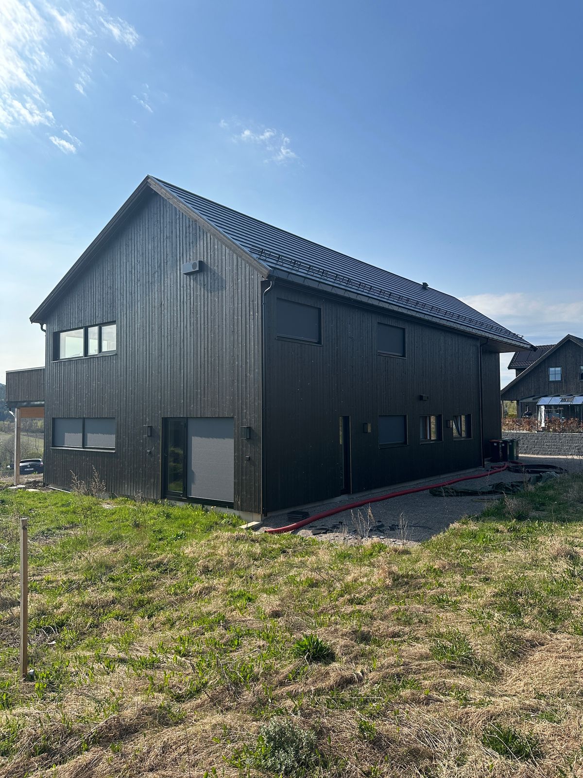 Nytt hus med sort stående kledning og saltak