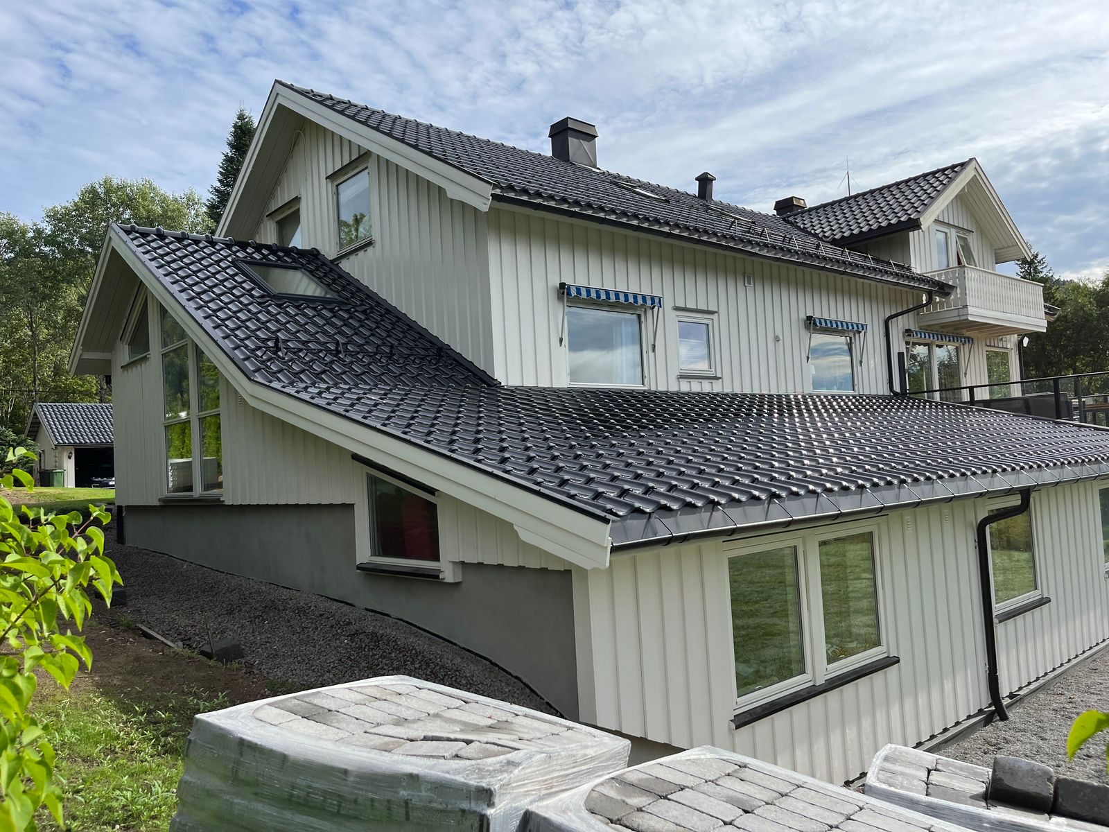 Hvitt hus med nytt tilbygg og sort takstein