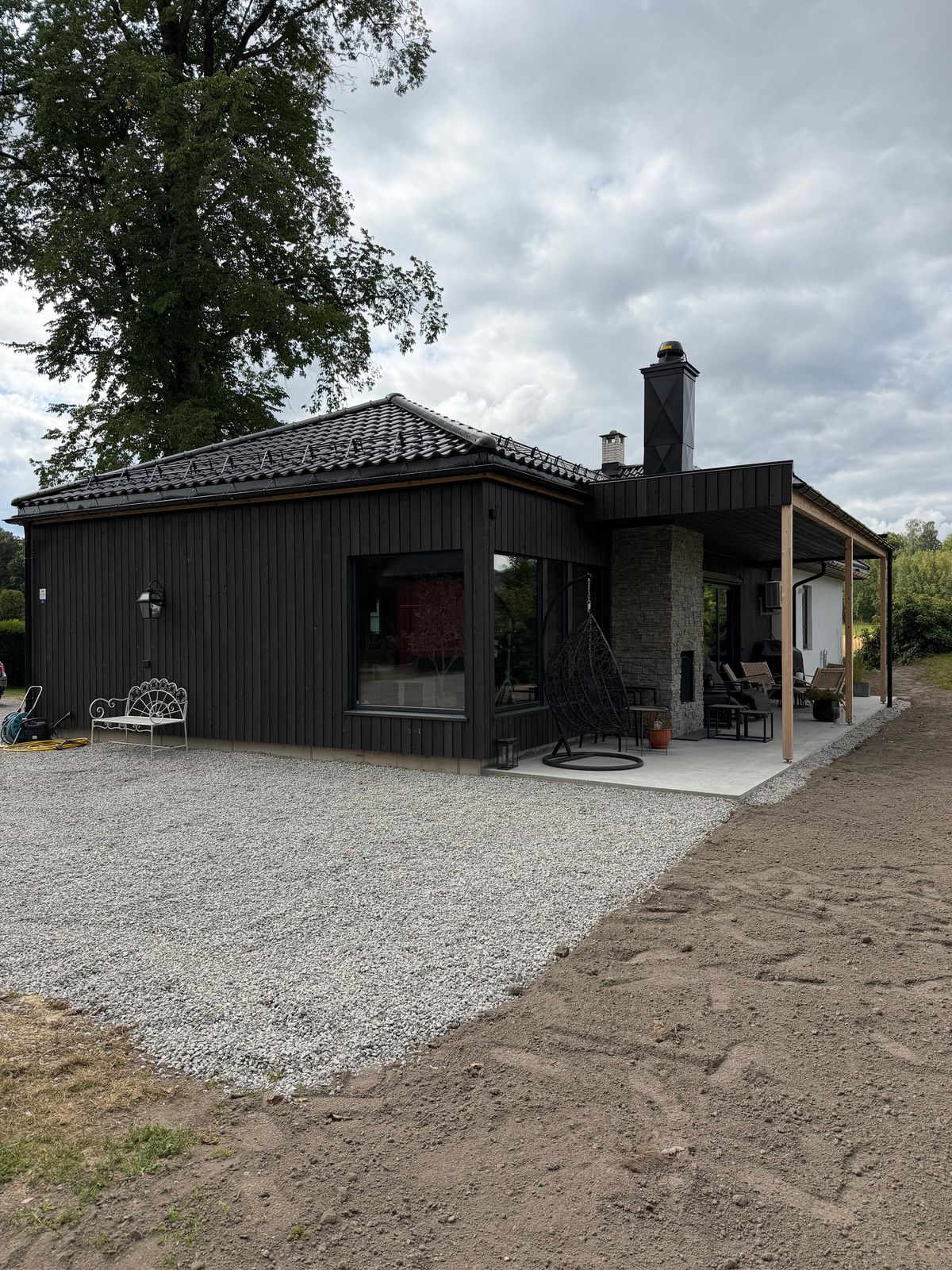 Mørkt hus med nytt tilbygg og overbygd terrasse