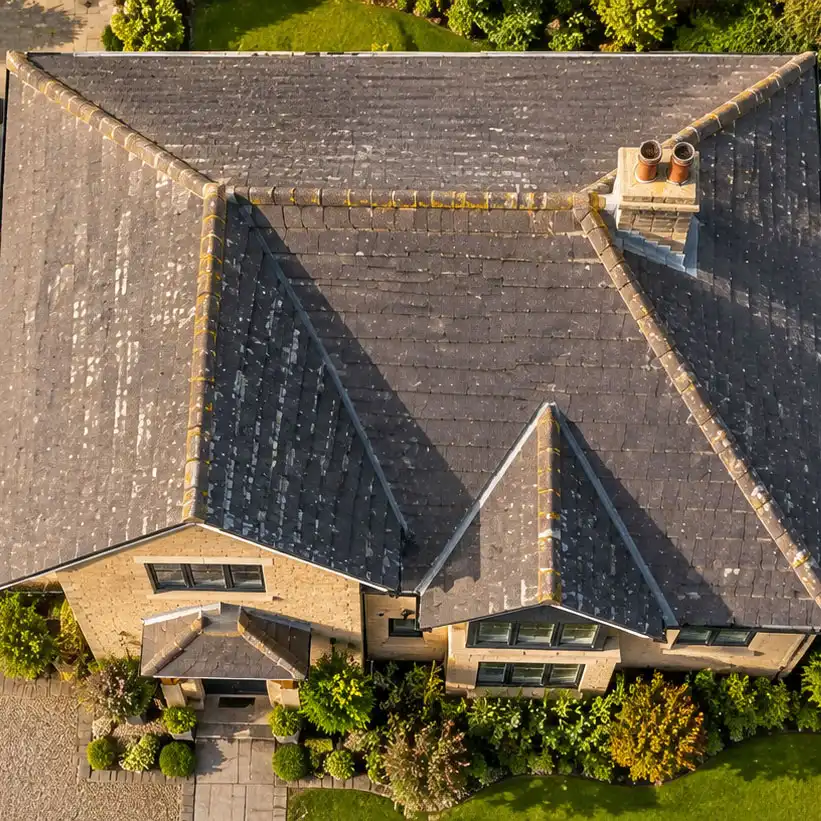 Top-down aerial view of a UK residential property showing full roof structure with tiles, ridges, valleys, chimney stack, and flat roof extension.