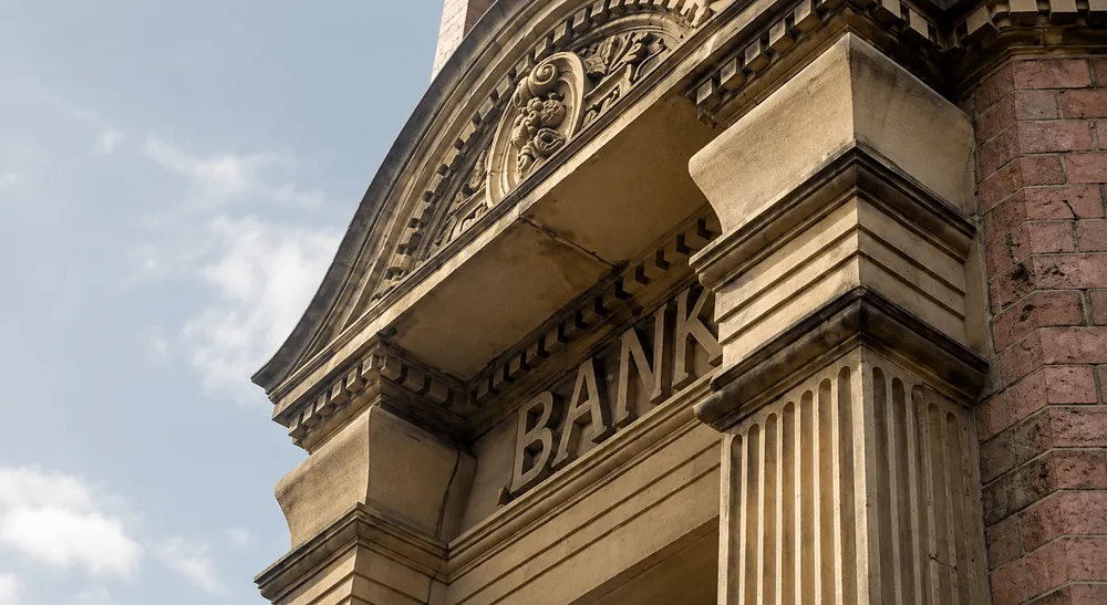 Stone facade of a traditional bank building with the word BANK carved above the entrance