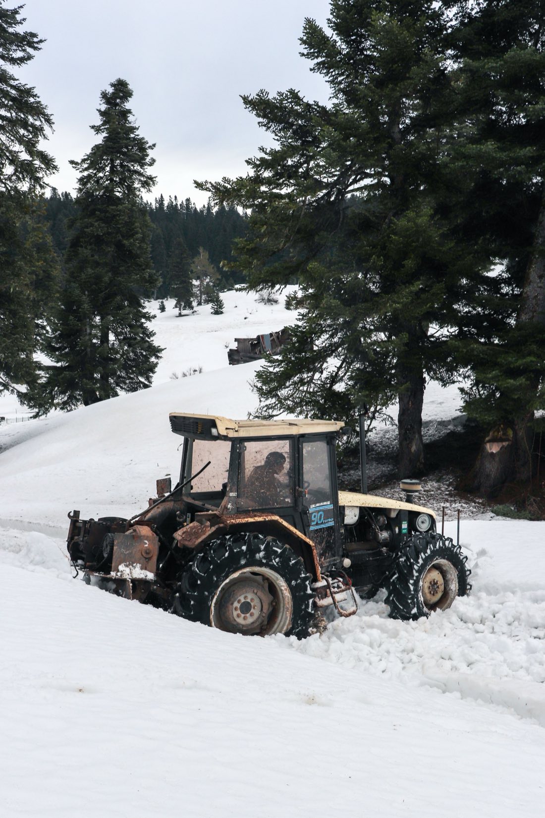 Traktor med brøyteutstyr i vinterskog