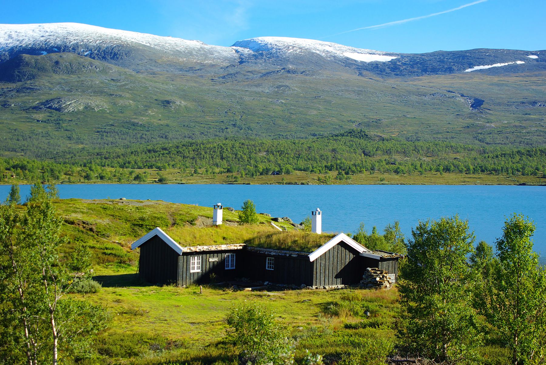 Hytter med torvtak ved et fjellvann om sommeren
