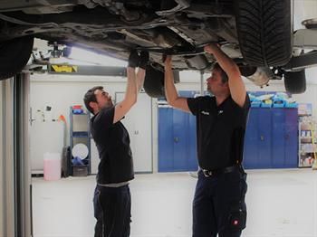KFZ-Meister Jörg Krista und KFZ-Mechatroniker Frederic Heller arbeiten an einem Auto