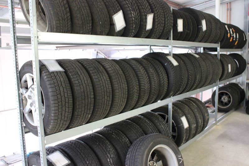 Regal mit drei Reihen gelagerten Autoreifen in einer Werkstatt oder einem Lagerraum.