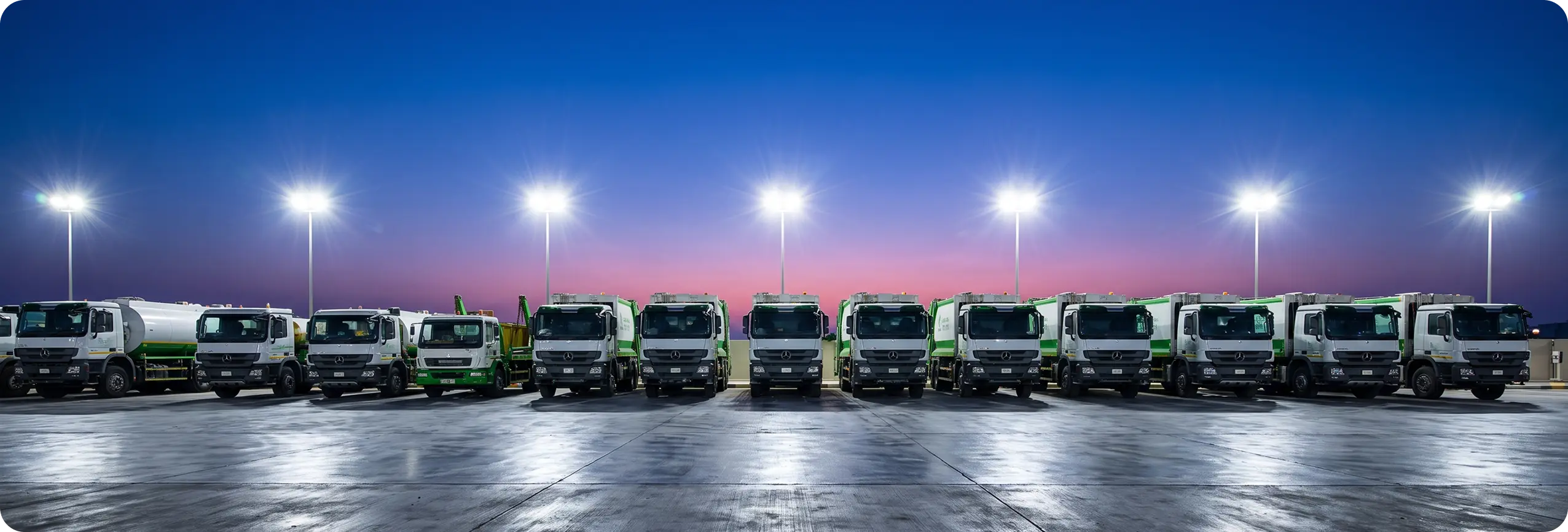 Green Arabia waste collection fleet lined up at dusk