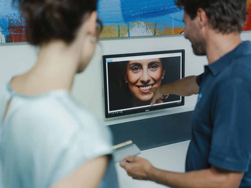 Zahnarzt zeigt Patientin am Bildschirm eine digitale Simulation ihres neuen Lächelns – präzise Digital Smile Design Planung bei den Q-Zahnärzten Freiburg.