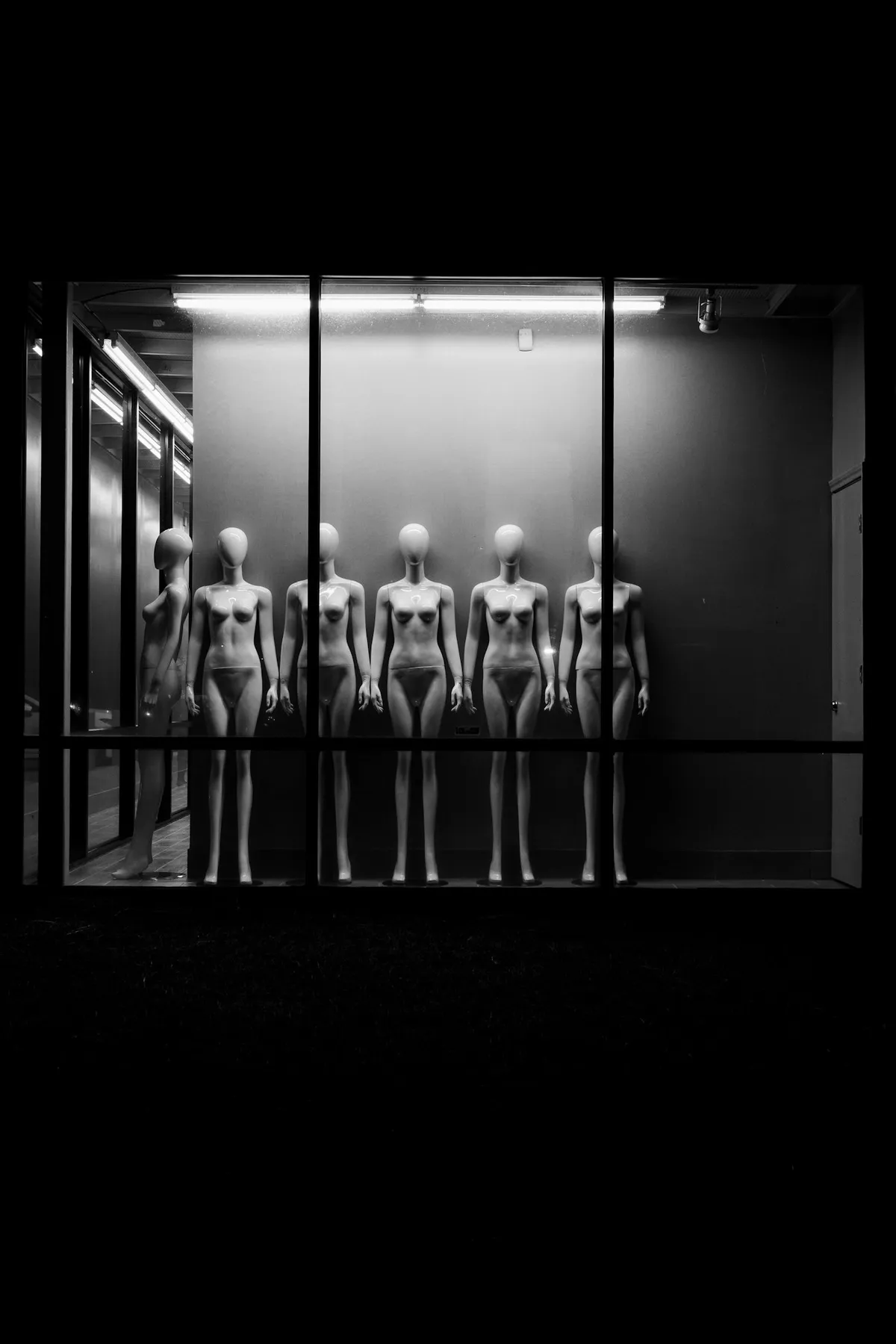 Mannequins in a row, one dark window