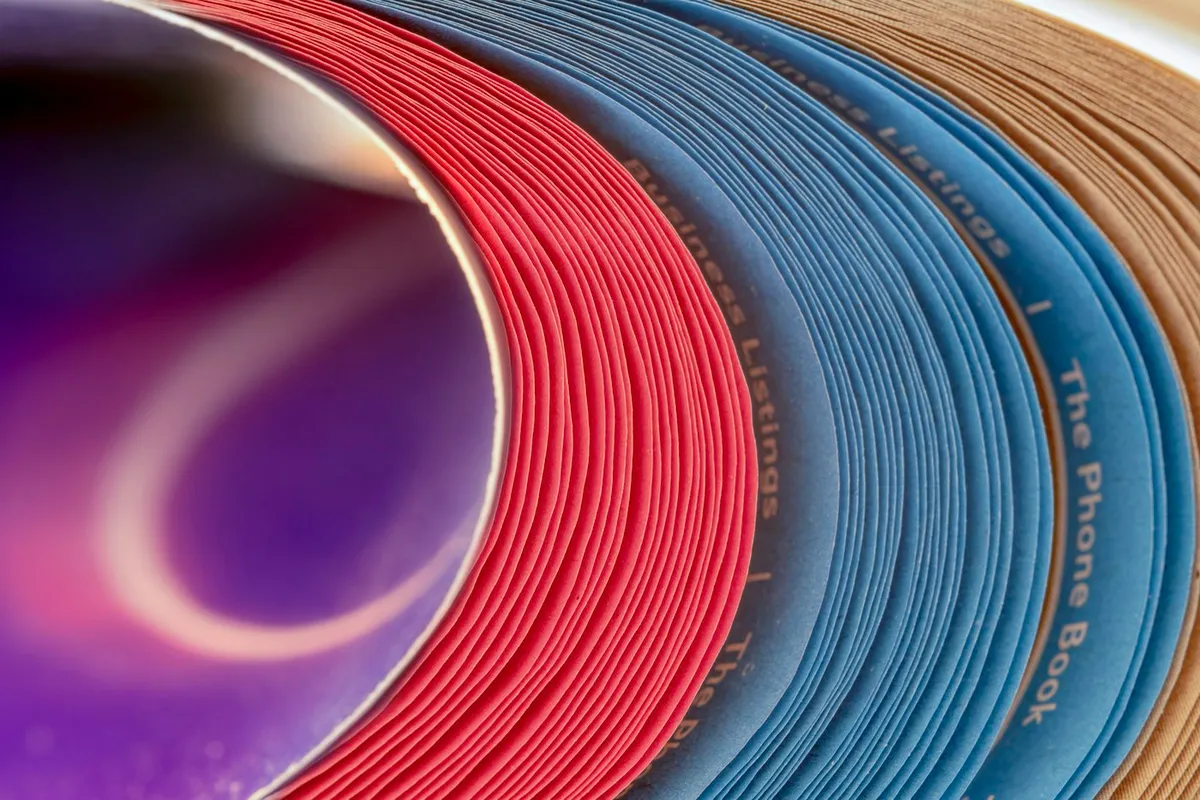 A thick directory fanned open, its sections marked by bands of colour printed on the page edges
