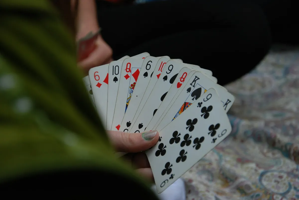 A hand holding playing cards fanned out so only the corner indices show