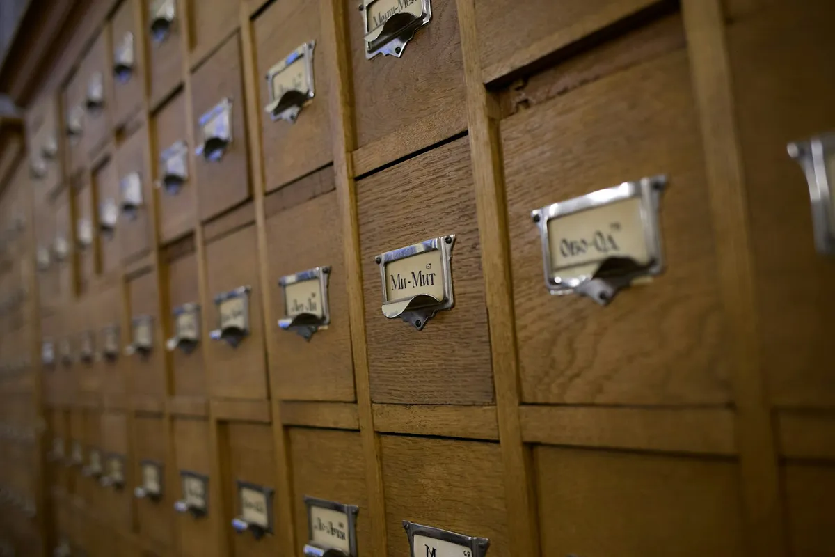 A wall of wooden card catalogue drawers, each with a small metal label holder