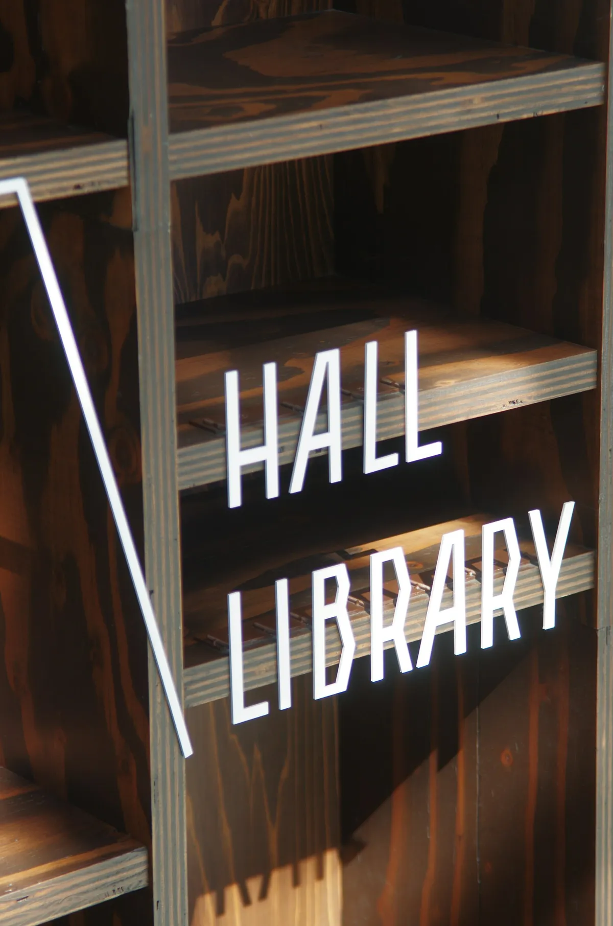 A hall sign mounted above wooden library shelving