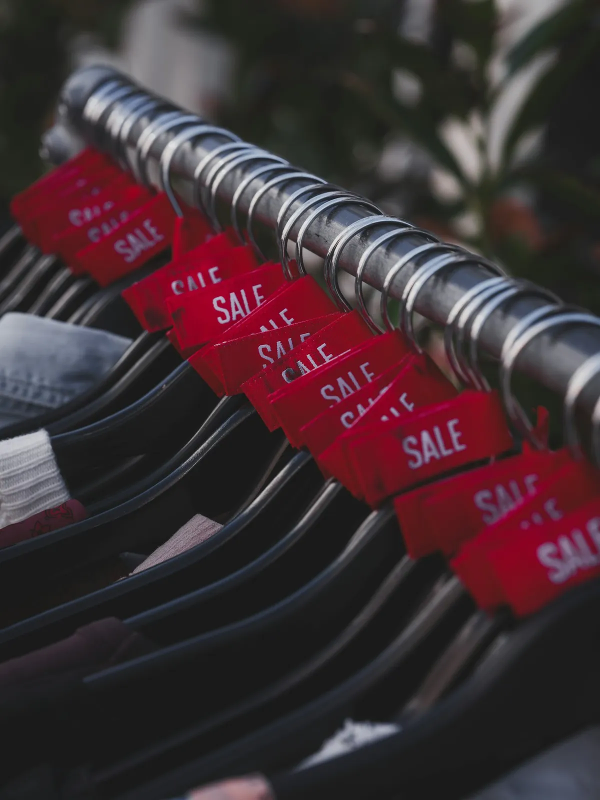 Red sale tags hanging from every garment along a clothing rail
