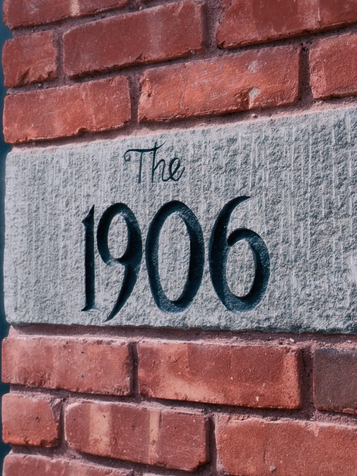 A carved stone plaque reading the 1906 set into a red brick wall