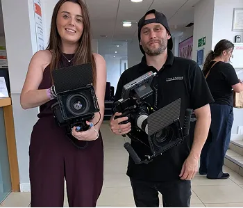 man and woman holding cameras and posing for picture