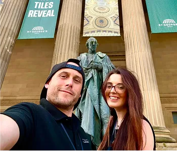 man and woman posing for selfie in front of a statue