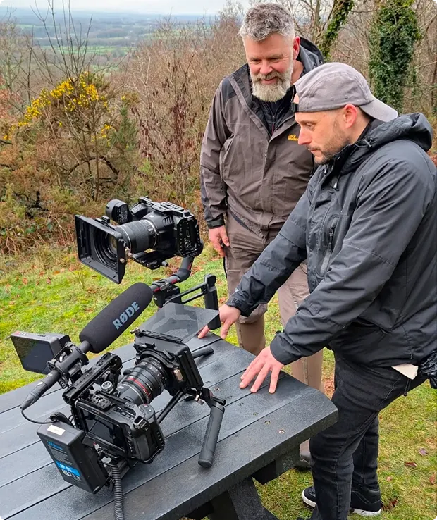two men checking footage on a video camera's screen