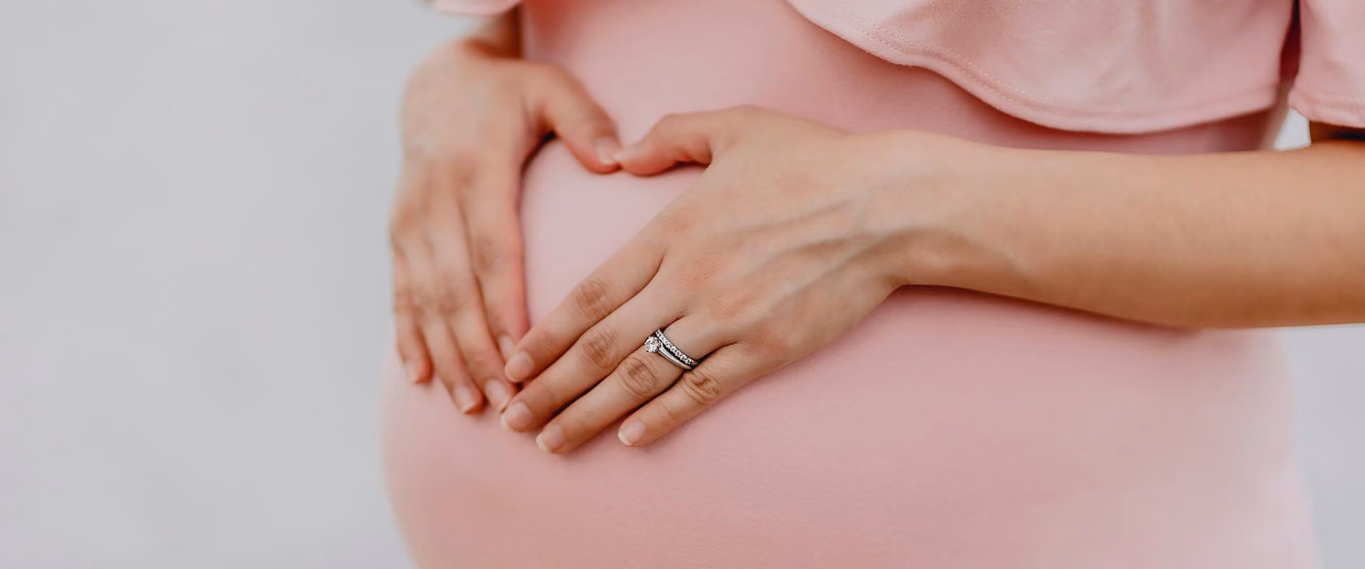 A pregnant woman with her hands on her bump.